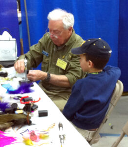 Man teaches a boy to tie a fly