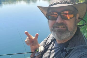 A man in a hat and sunglasses is holding his fishing rod.