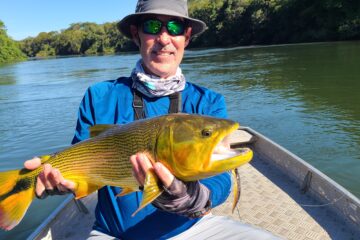 Man holding large fish on boat.