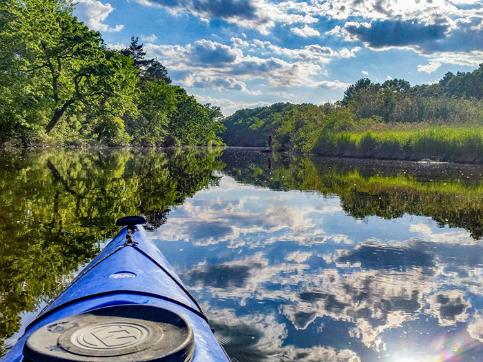 Blue kayak on calm reflective river.